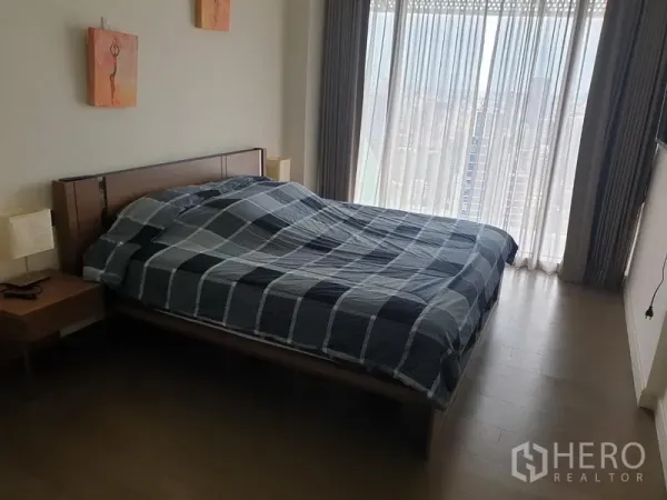 Condominium for rent in Pathum Wan, Bangkok - Second bedroom with wooden floor, large window and soft natural light.