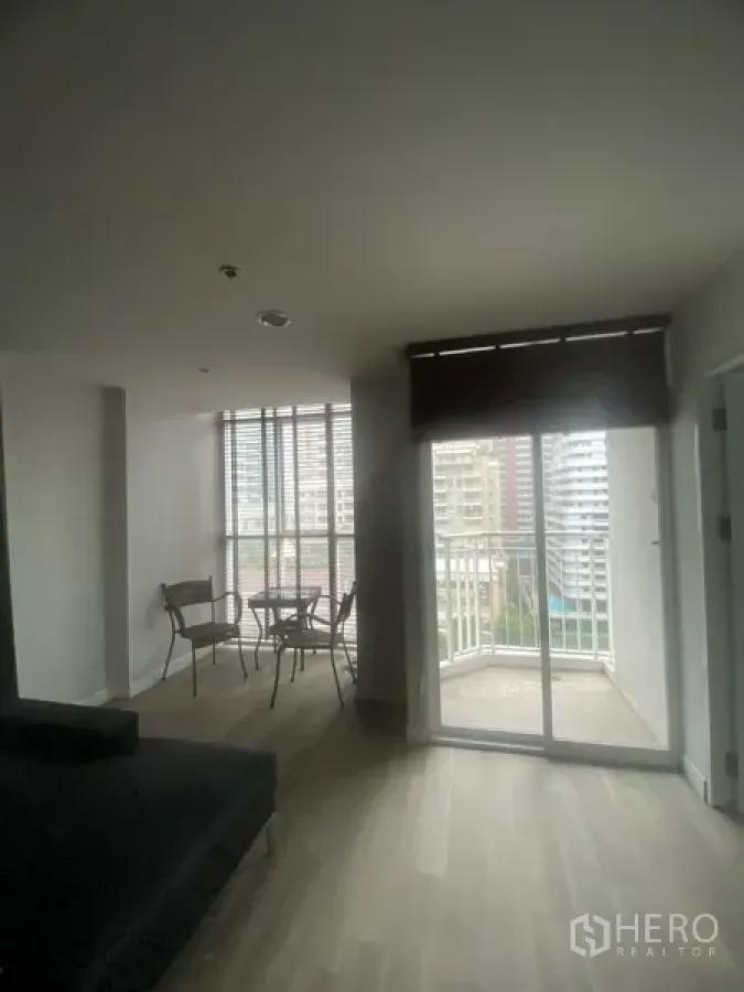 Condominium for rent in Pathum Wan, Bangkok - Open living and dining area with sliding doors to a small balcony and skyline views near BTS Chitlom.
