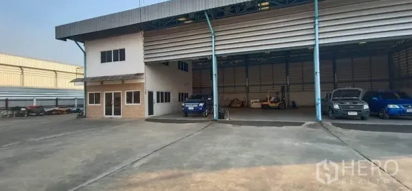 Warehouse for rent in Khlong Luang, Pathum Thani - Covered loading bays with roller shutter doors and a small office block at the warehouse front.