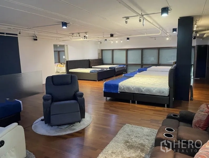 Retail Space for rent - Bright showroom floor with multiple display zones, reclining chairs, spotlighting and polished wood floors.