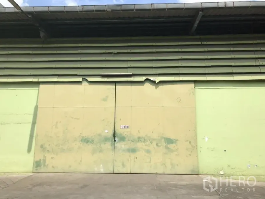 Warehouse for rent in Khlong Toei, Bangkok - Close-up of a large metal double loading door on a corrugated warehouse facade under an extended roof.