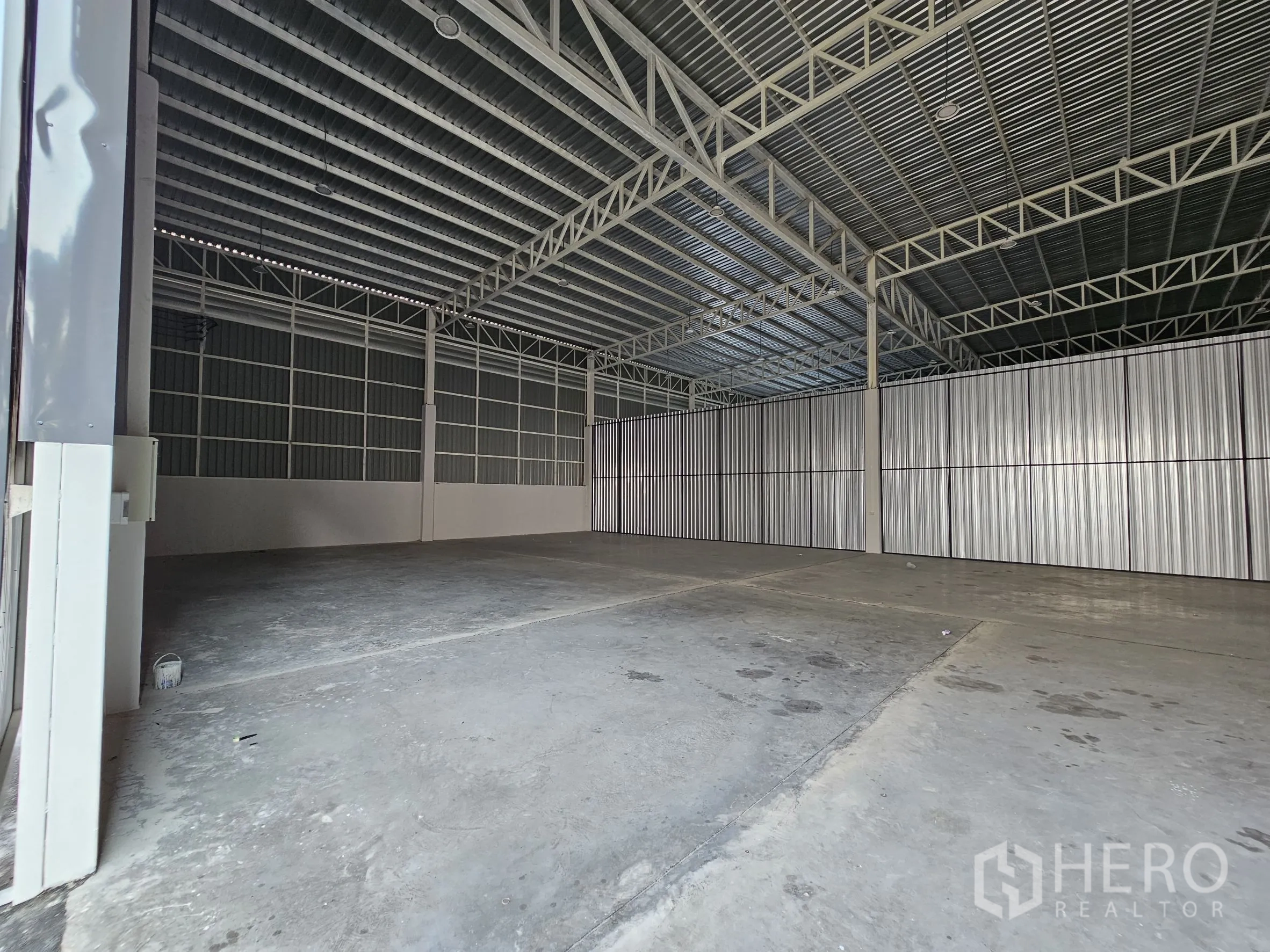 Warehouse for rent in Khlong Toei, Bangkok - Open warehouse interior with steel truss roof, corrugated walls, and concrete floor.
