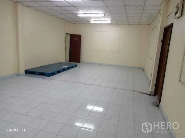 Warehouse for rent or sale in Mueang Samut Sakhon, Samut Sakhon - Open tiled space with ceiling lights and a plastic pallet on the floor.