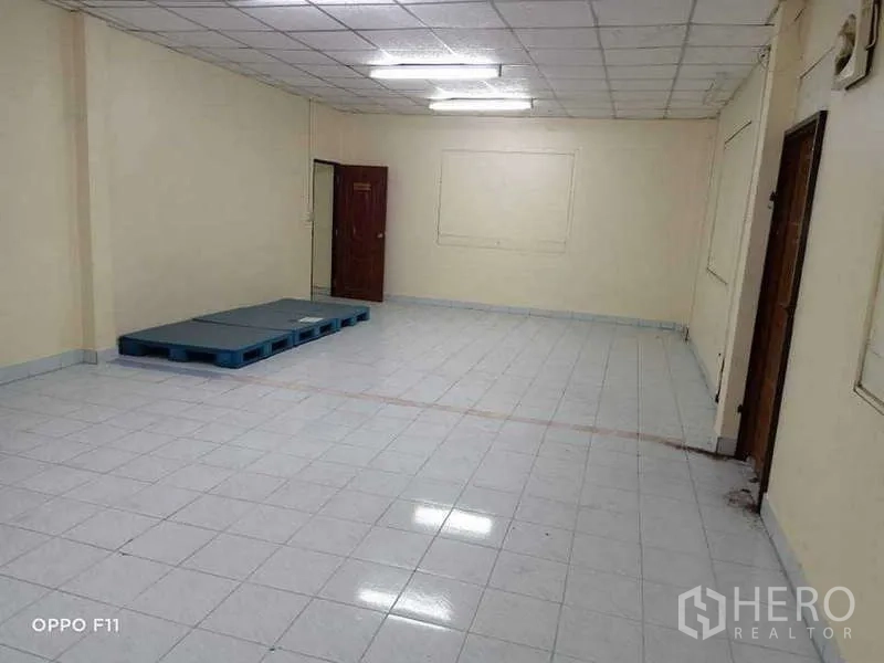 Warehouse for rent or sale in Mueang Samut Sakhon, Samut Sakhon - Open tiled space with ceiling lights and a plastic pallet on the floor.