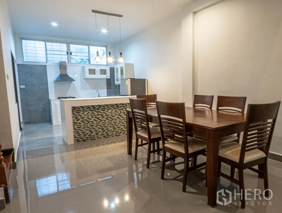 联排别墅 出租在Khlong Toei, Bangkok - 开放式餐厅配六人木餐桌，旁接带吊灯的厨房中岛。