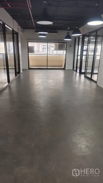 Office Space for rent in Pathum Wan, Bangkok - Open-plan office with polished concrete floor, glass partitions, pendant lights and sliding doors to a balcony with city views.