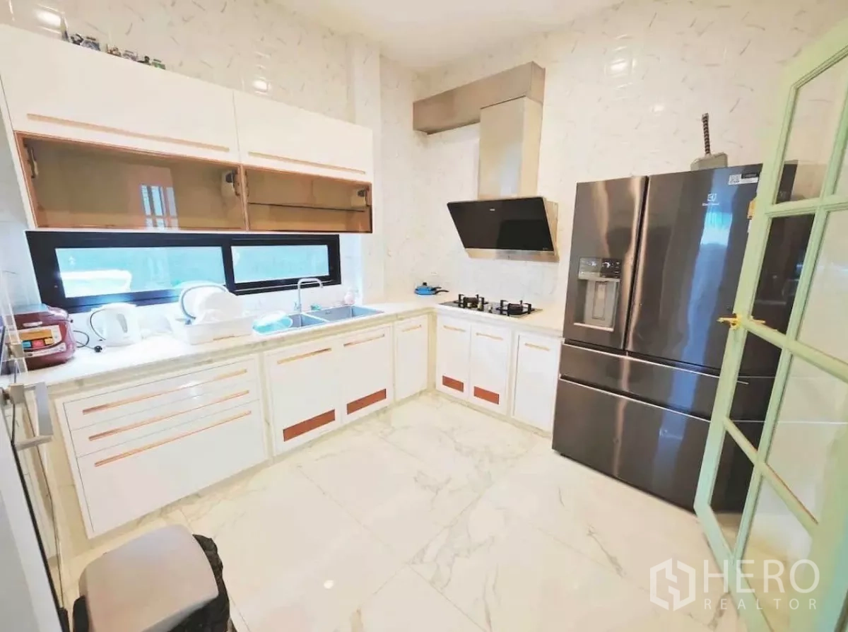 Detached House for rent in Phaya Thai, Bangkok - Modern L-shaped kitchen with marble-look tiles, stainless fridge and range hood.