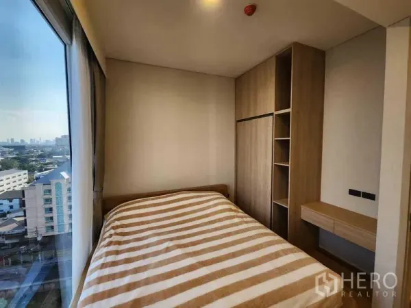 Condominium for rent in Khlong Toei, Bangkok - Second bedroom with built-in wardrobe and desk by panoramic window.