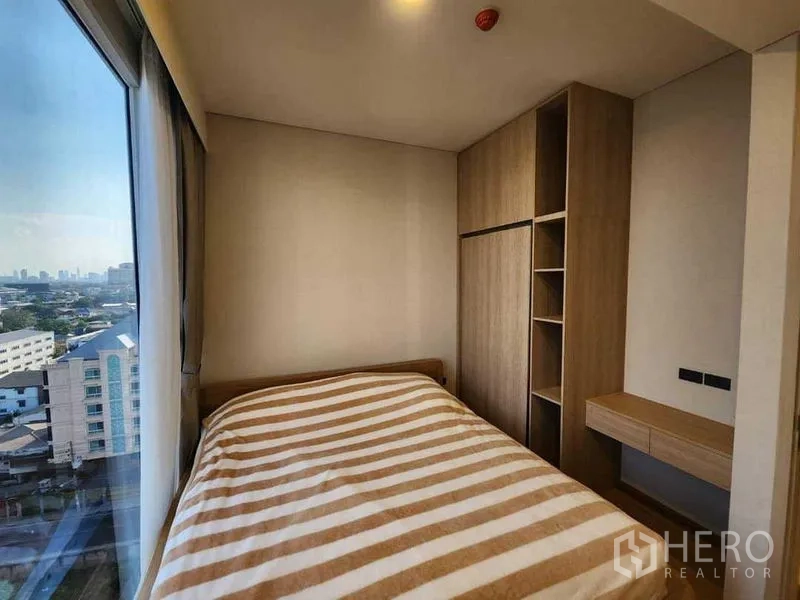 Condominium for rent in Khlong Toei, Bangkok - Second bedroom with built-in wardrobe and desk by panoramic window.
