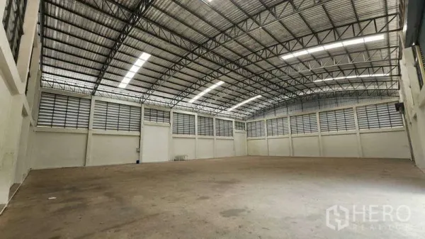 Factory for rent in Ban Phaeo, Samut Sakhon - Open-plan warehouse space showing clear-span steel trusses, bright roof lights and ventilation panels.