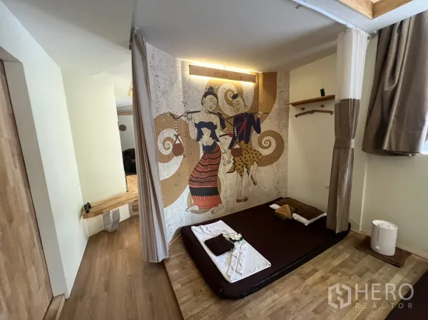 Retail Space for rent in Khlong Toei, Bangkok - Compact treatment room with wood floors, platform bed and Thai‑style decorative mural.