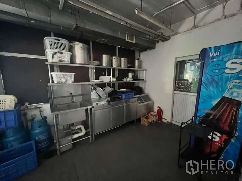 Shophouse for rent or sale in Khlong Toei, Bangkok - Utility room with stainless sinks, open shelving and gas cylinders for kitchen use.
