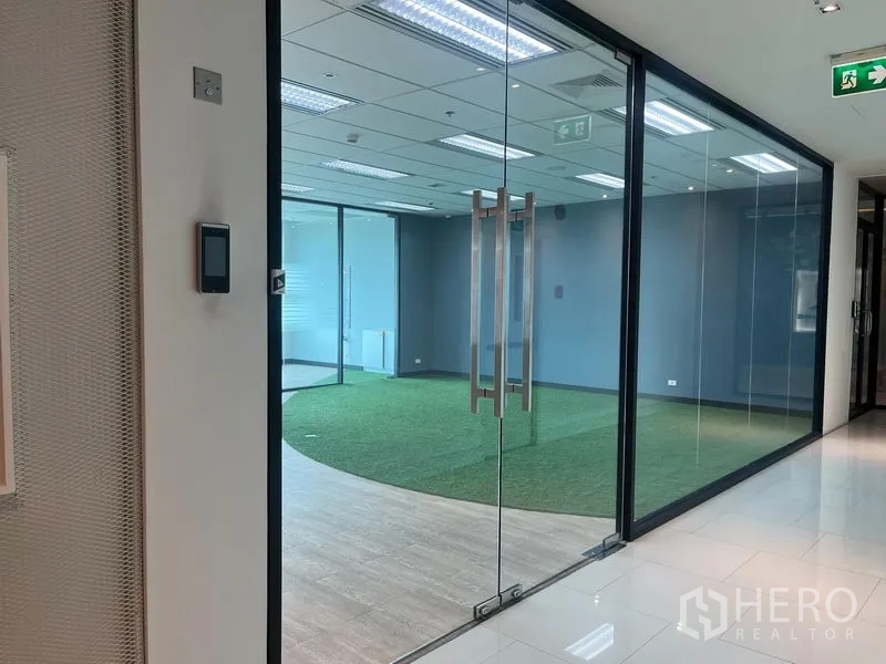 Office Space for rent in Chatuchak, Bangkok - Entry through double glass doors to an office with turf area and floor-to-ceiling glass partitions.
