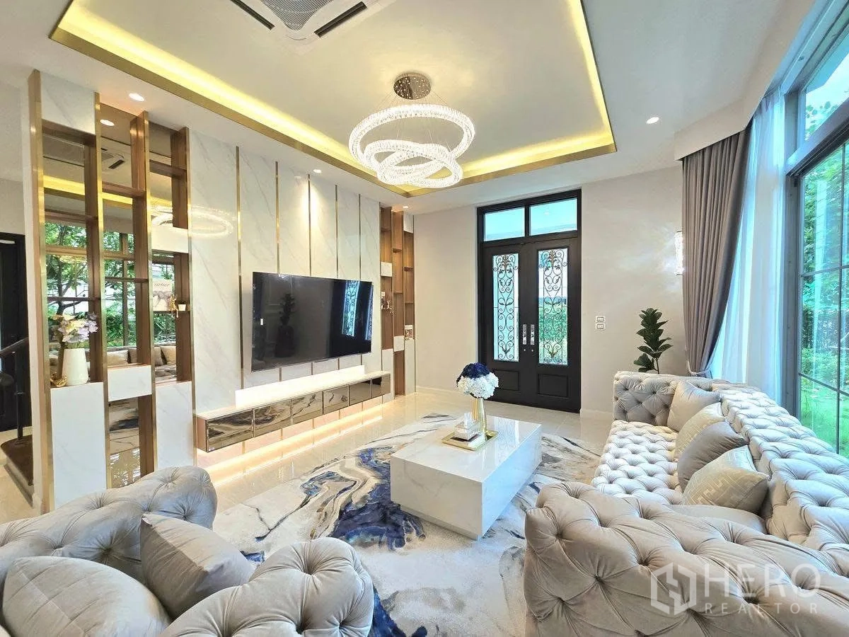 Detached House for rent or sale in Bang Phli, Samut Prakan - Living room TV wall with marble panels, large windows, double entry doors and plush sofas.
