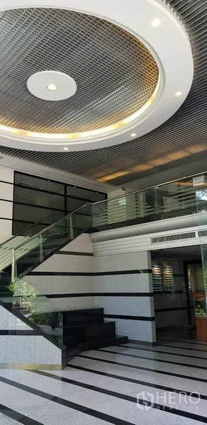 办公空间 出租在Khlong Toei, Bangkok - 现代大堂，设玻璃楼梯、条纹地面与环形吊顶。