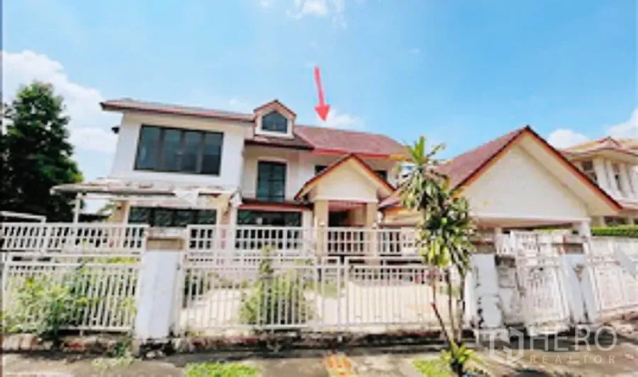 Detached House for sale in Khan Na Yao, Bangkok - Front view of a two-storey detached house with red gable roof and a white gated fence and driveway.