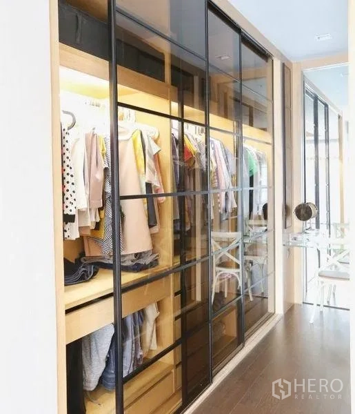 Detached House for rent or sale in Bang Kapi, Bangkok - Walk-in closet with illuminated wooden shelving and glass sliding doors.