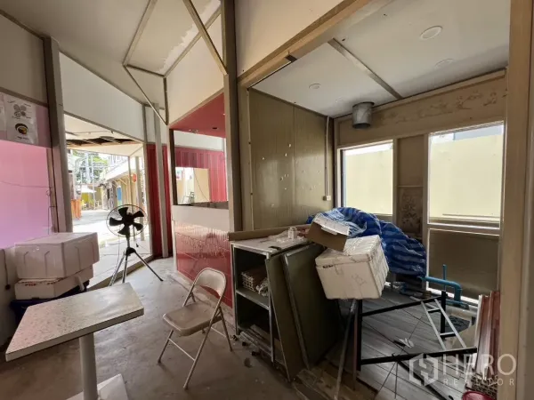 Retail Space for rent in Khlong Toei, Bangkok - Unfinished shop area with windows, counter space and fan, looking out to colorful neighboring storefronts.