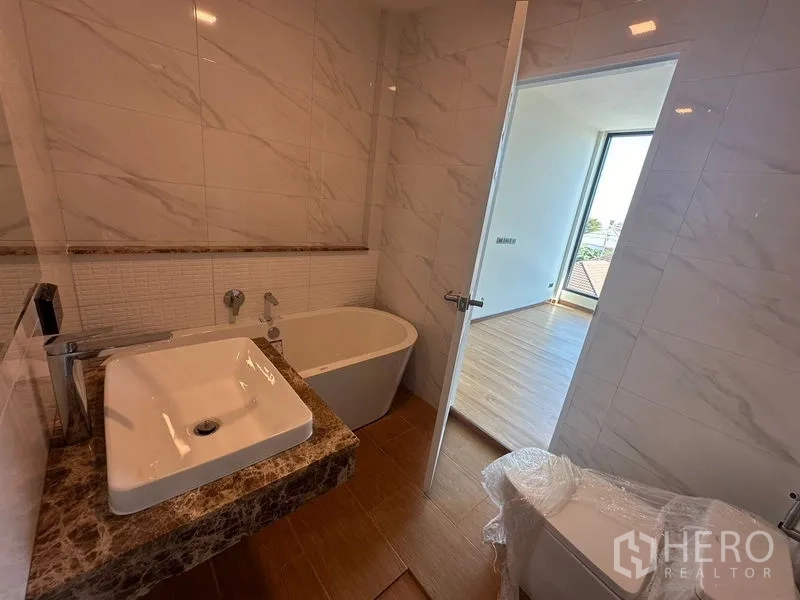 Home Office for rent in Wang Thonglang, Bangkok - Bathroom featuring a bathtub, marble vanity, and door connecting to the bedroom.