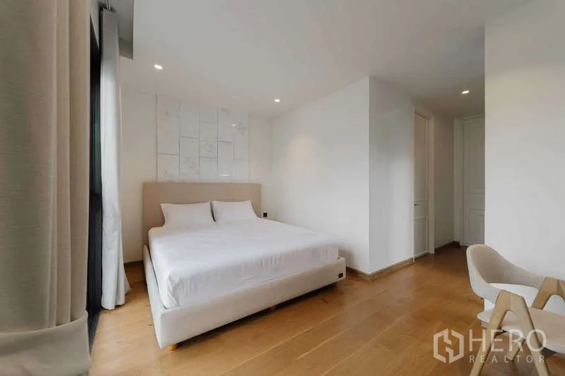 Townhouse for rent or sale in Watthana, Bangkok - Spacious bedroom with a king bed, wood flooring, and large windows.