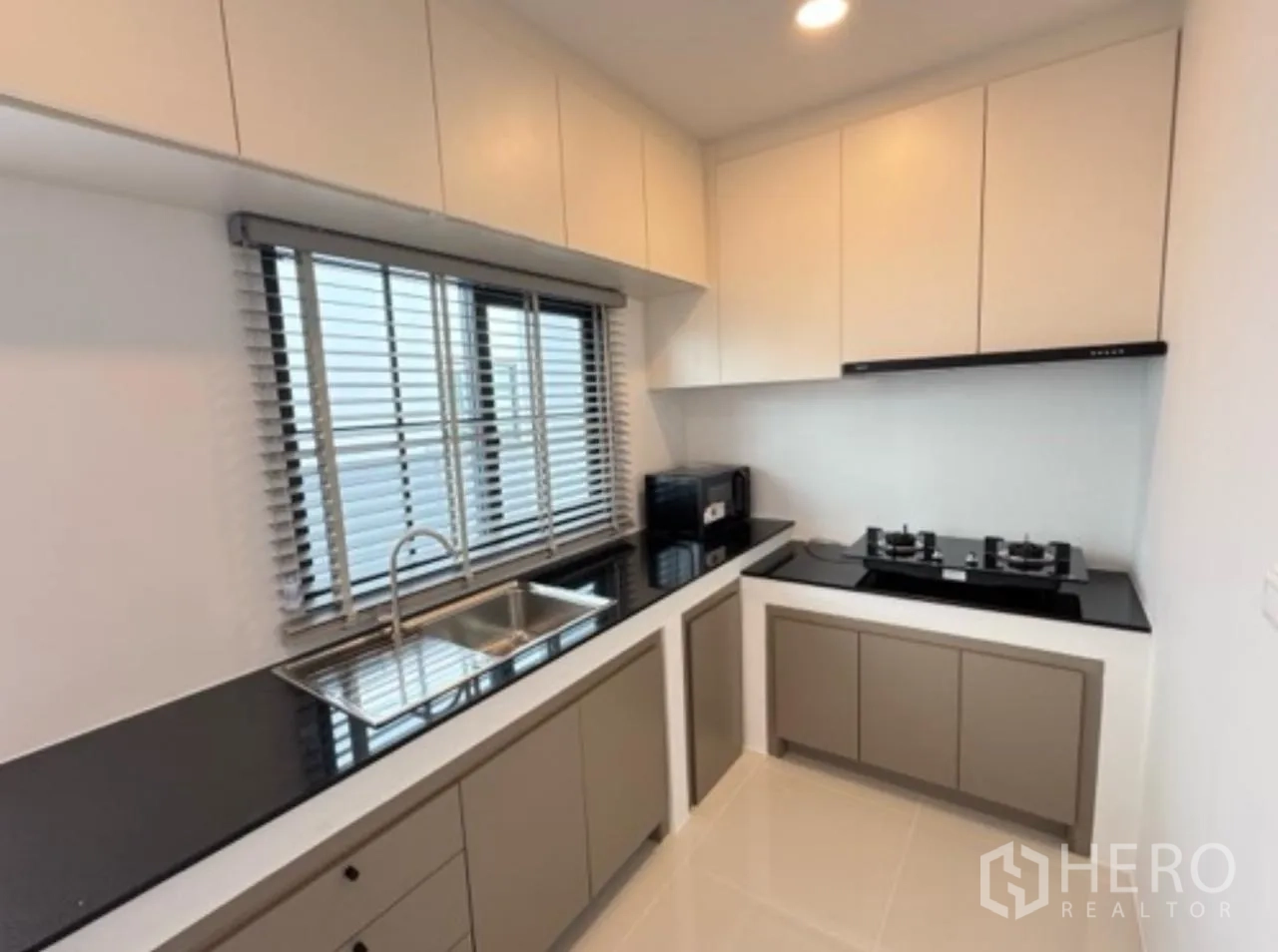 Detached House for rent in Bang Phli, Samut Prakan - Modern closed kitchen with L-shaped counters, sink, gas hob and cabinets.