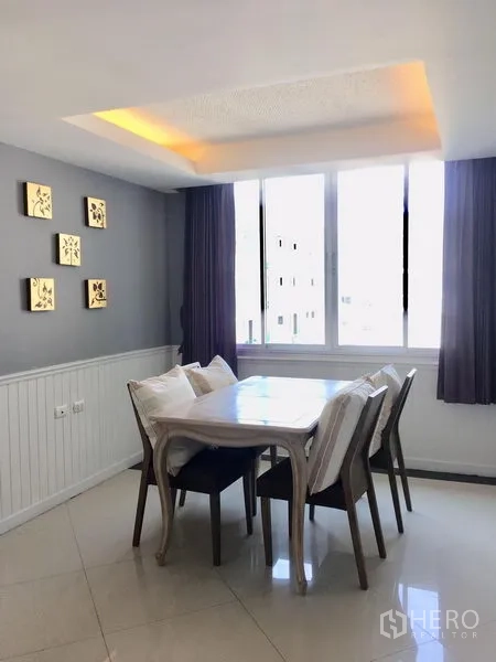 Condominium for rent in Khlong Toei, Bangkok - Sunlit dining corner with four chairs beneath cove lighting.