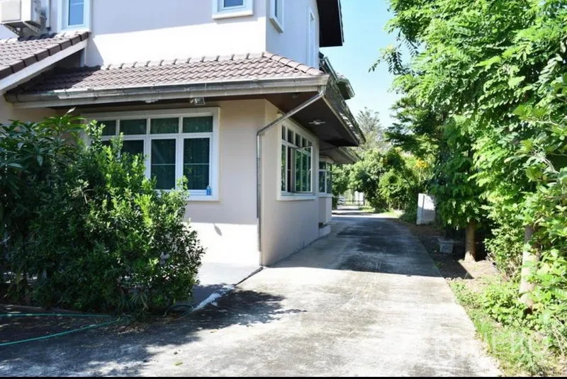 Detached House for sale in Sai Mai, Bangkok - Side exterior of a two-storey detached house with a long driveway and mature greenery.