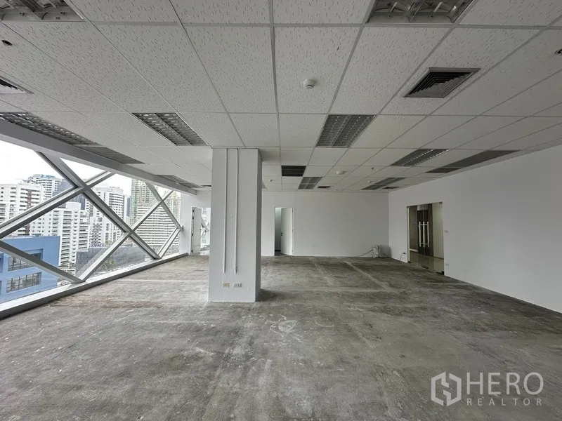 办公室 for rent in Watthana, Bangkok - 临窗工作区，中央立柱与城市背景。