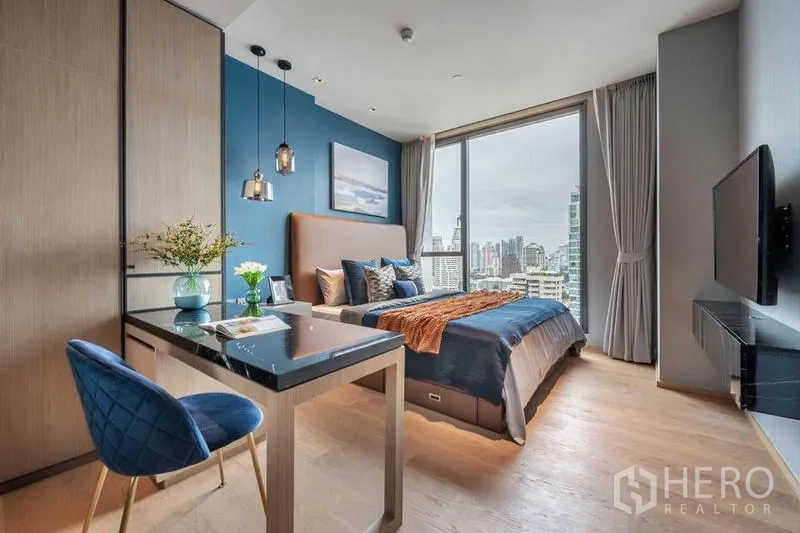 Condominium for rent in Khlong Toei, Bangkok - Bright bedroom with floor-to-ceiling window, skyline view and work desk