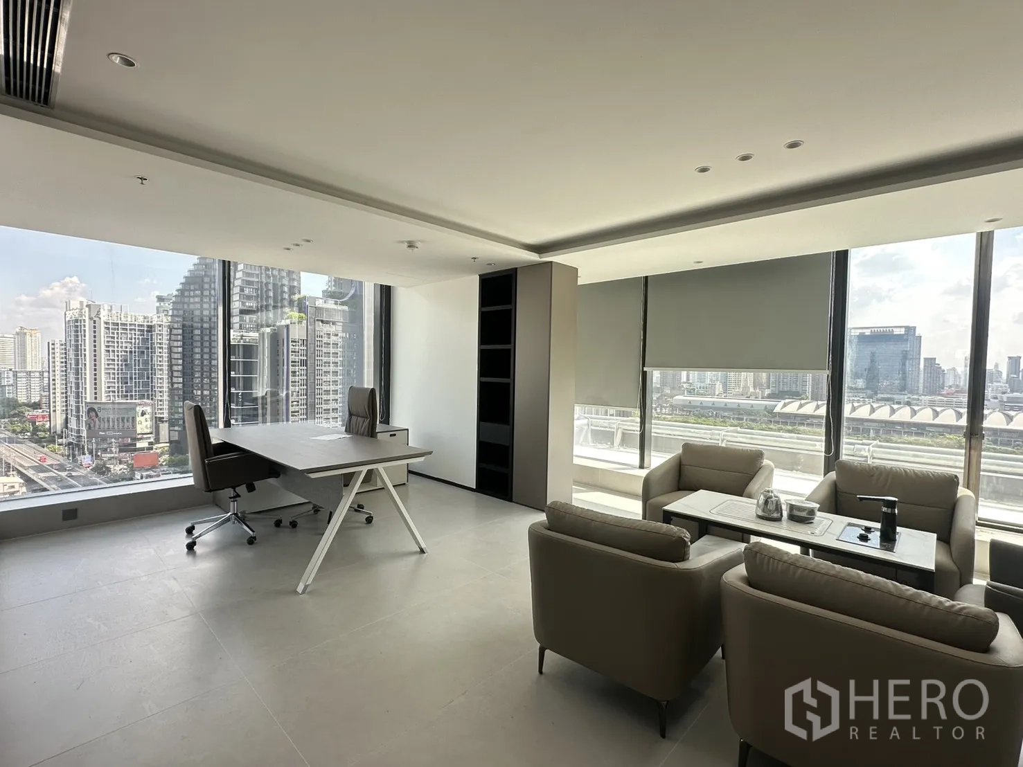 Office Space for rent in Din Daeng, Bangkok - Corner executive room with a desk, sofa seating, and wide city view windows.