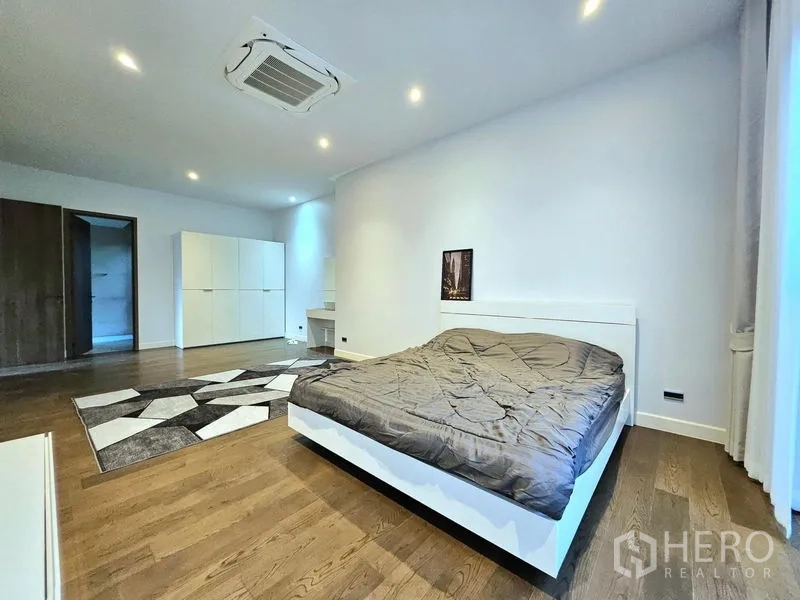 Detached House for rent in Bang Kapi, Bangkok - Large primary bedroom with wood flooring, rug and cassette air‑conditioning