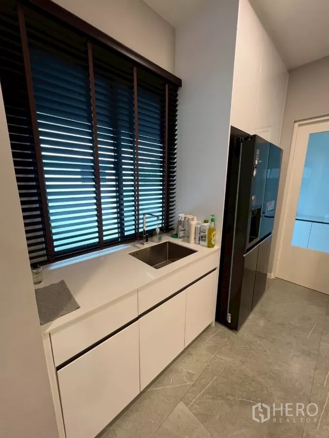 Detached House for rent in Samut Prakan - Secondary prep area with sink beneath a window and dark blinds.