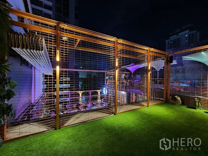 Retail Space for rent - Rooftop deck with artificial grass, metal lattice frame and night city views.