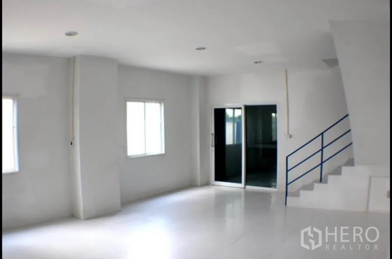 Factory for rent in Pak Kret, Nonthaburi - Open-plan office space with windows, recessed lighting and blue-railed stairs.