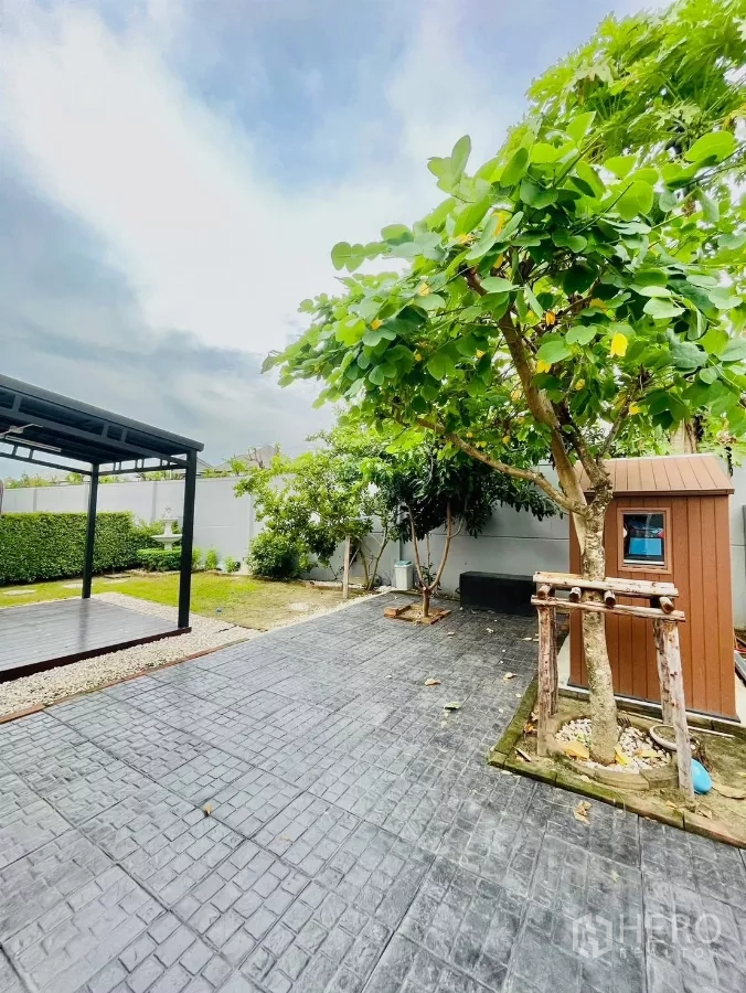 Detached House for rent in Prawet, Bangkok - Paved patio beside mature trees with a storage shed and open-frame gazebo.