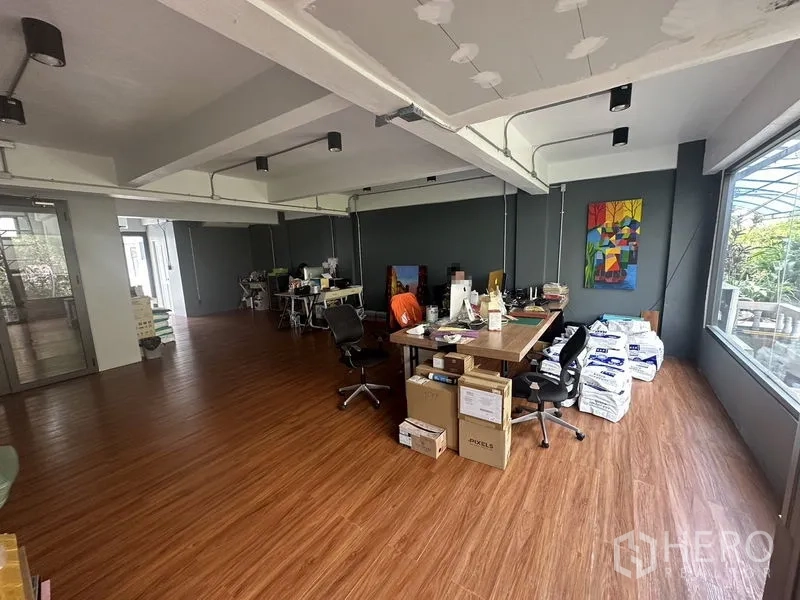 Home Office for rent in Sathon, Bangkok - Open-plan workspace with wood floors, exposed beams and a large window providing natural light.