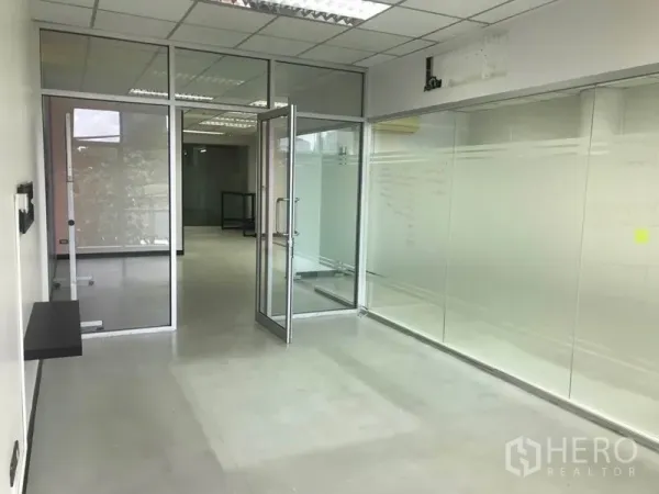Office Space for rent in Khlong Toei, Bangkok - Hallway with glass partitions leading to a meeting room with a hinged glass door and frosted panels.