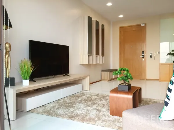 Condominium for rent or sale in Khlong Toei, Bangkok - Modern media wall with large flat-screen TV, storage and entrance door in the living area.