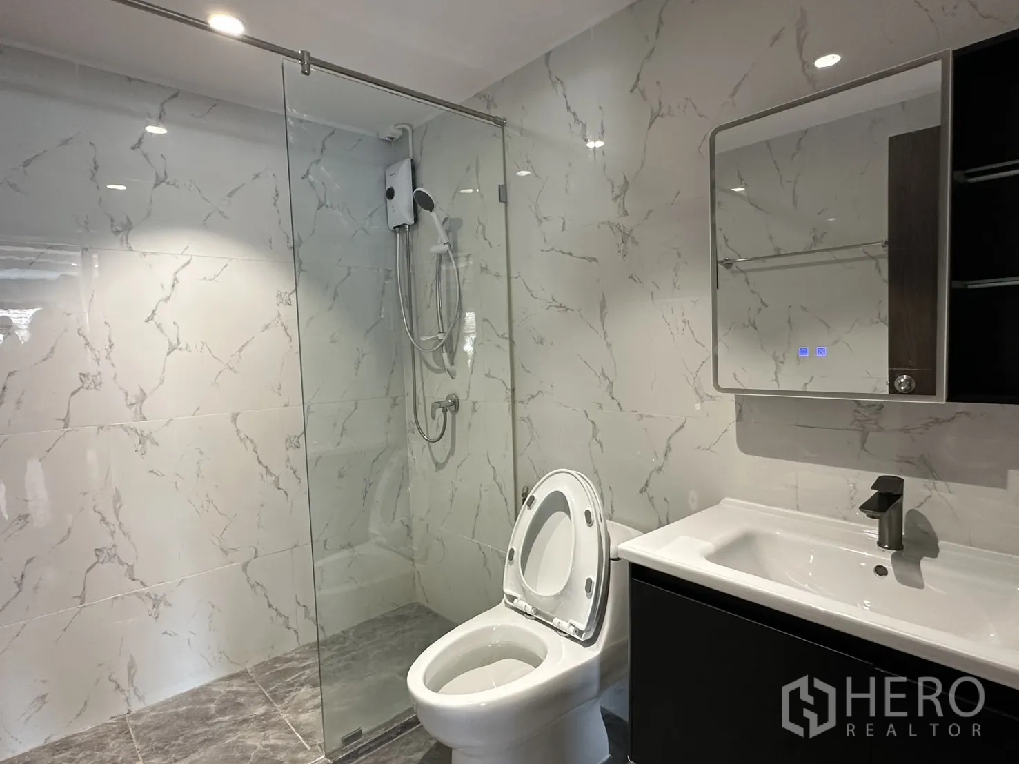 Home Office for rent in Watthana, Bangkok - Bathroom featuring a glass-enclosed shower and marble-look white tiles.