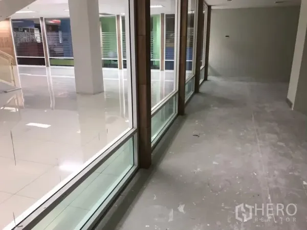 Office Space for rent in Bang Rak, Bangkok - Open-plan office with floor-to-ceiling glass partition facing a bright tiled common area.
