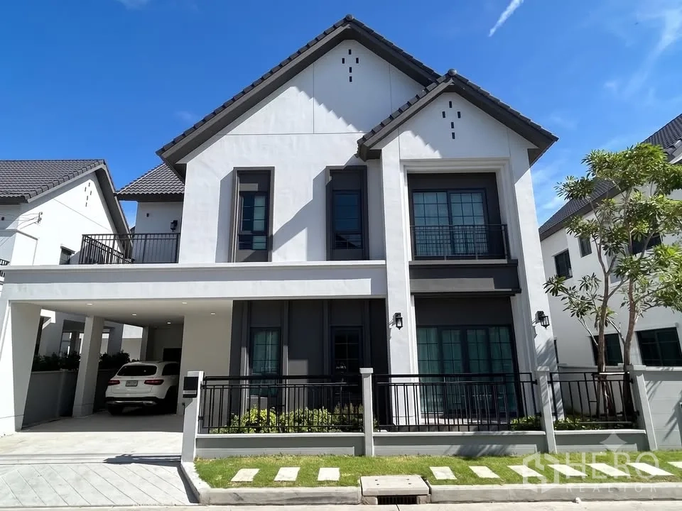 Detached House for rent in Bang Phli, Samut Prakan - Modern two-storey detached house with covered carport, small lawn, and black-framed windows.