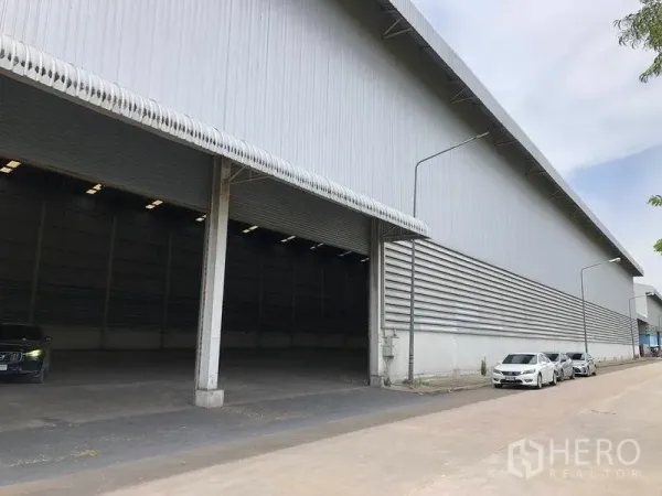 Warehouse for rent in Phra Nakhon Si Ayutthaya - Covered loading bays along a long warehouse facade with a wide driveway for trucks.