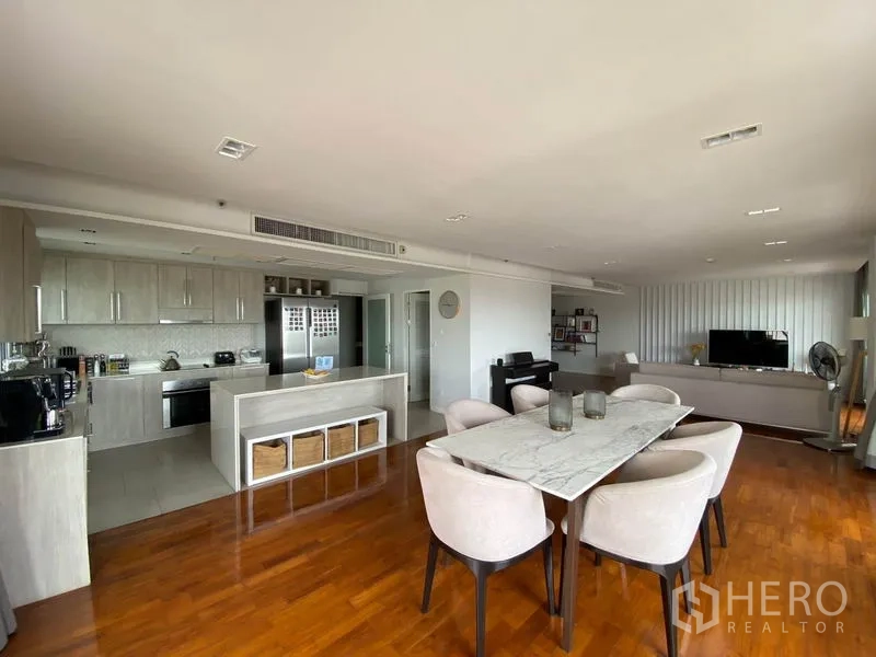 Condominium for rent in Sathon, Bangkok - Open-plan dining and living area with marble dining table beside a light-wood kitchen and island.