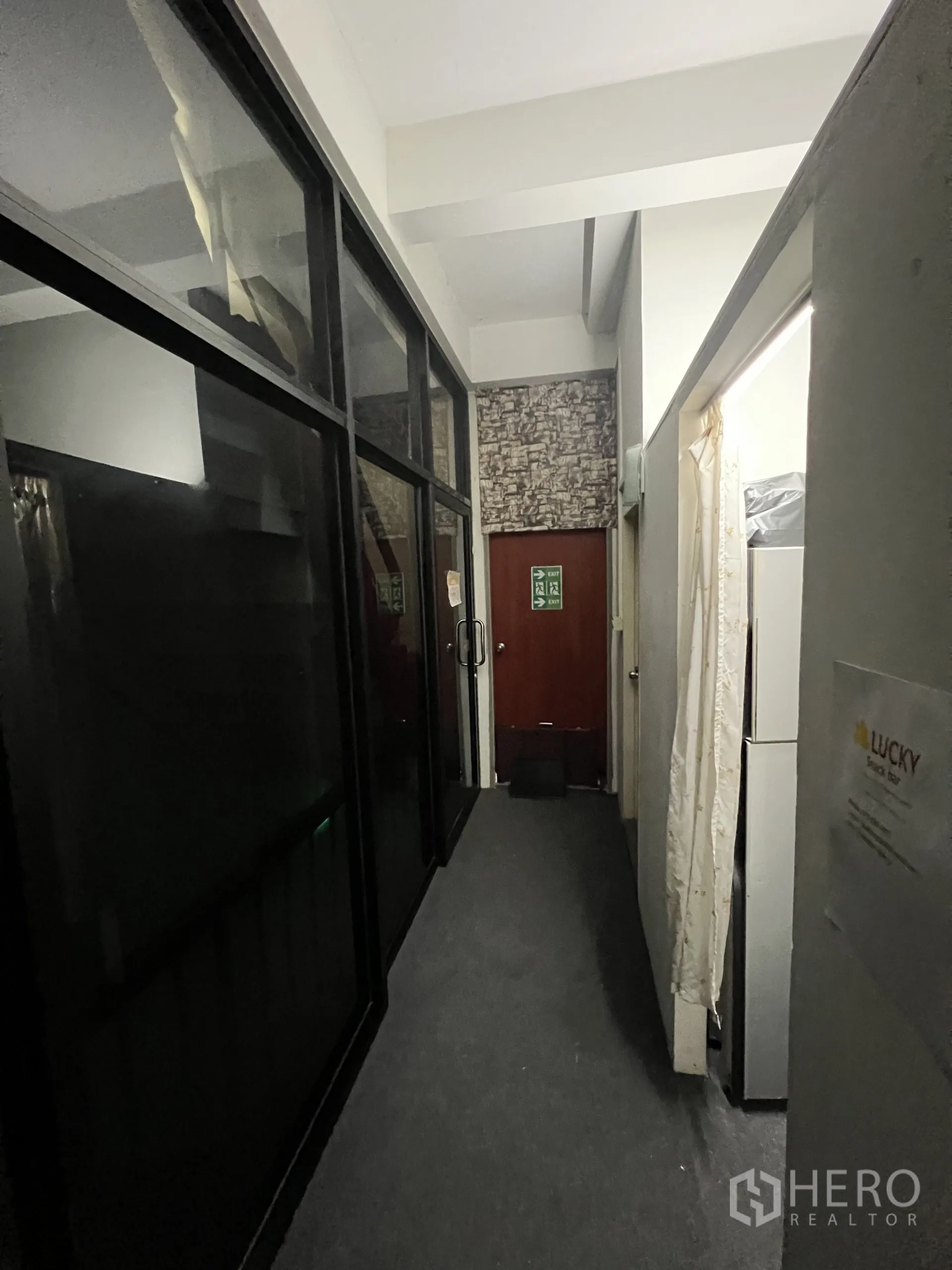 Shophouse for rent in Khlong Toei, Bangkok - Carpeted hallway with dark glass partitions leading to a rear door.