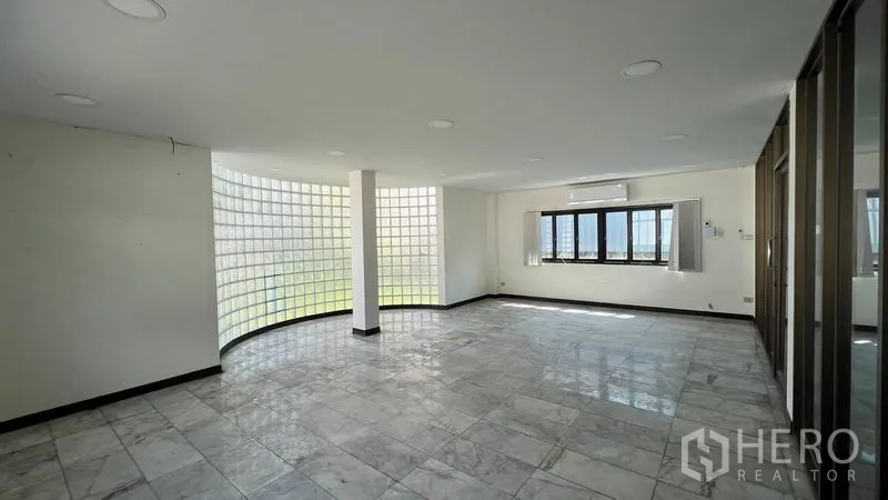 Warehouse for rent in Thanyaburi, Pathum Thani - Bright office interior with curved glass-block wall, tiled flooring, and windows for natural light.