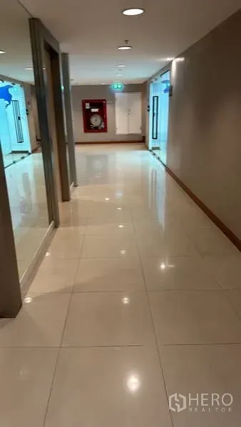 Office Space for rent - Well-lit office corridor with polished tile floor, glass entrances and a fire hose cabinet.