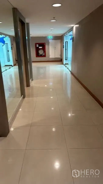 Office Space for rent - Well-lit office corridor with polished tile floor, glass entrances and a fire hose cabinet.