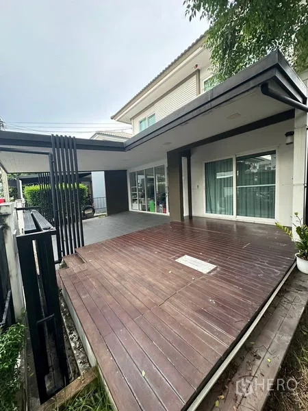 Detached House for sale in Prawet, Bangkok - Wooden terrace beside sliding doors and boundary wall, ready for outdoor seating.