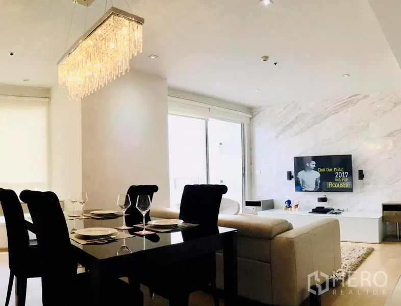 Condominium for rent or sale in Watthana, Bangkok - Open-plan dining and lounge area with a chandelier and floor-to-ceiling windows.