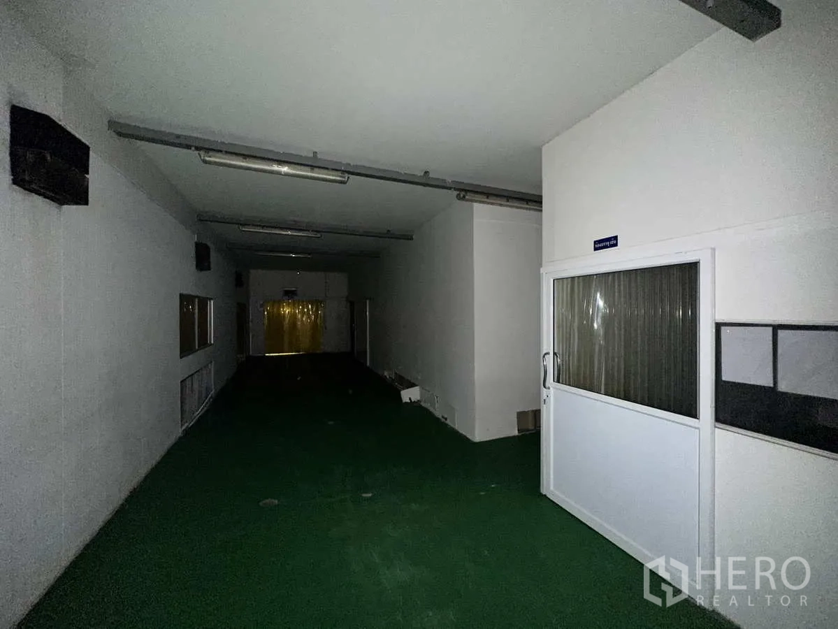 Factory for rent or sale in Bang Yai, Nonthaburi - Clean corridor with green floor leading to a processing room behind PVC curtain.